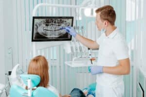 Dentist reviewing a dental X-ray with a female patient in a modern oral surgery clinic, emphasizing dental health and treatment planning.