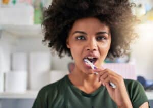 Smiling woman holding a toothbrush in the bathroom, representing daily dental care, oral hygiene, and cavity prevention for overall wellness
