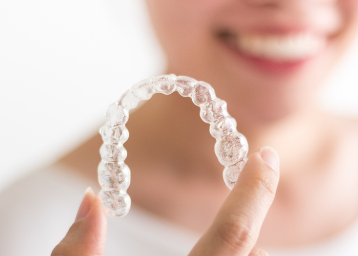 Woman holding a pair of Invisalign clear aligners